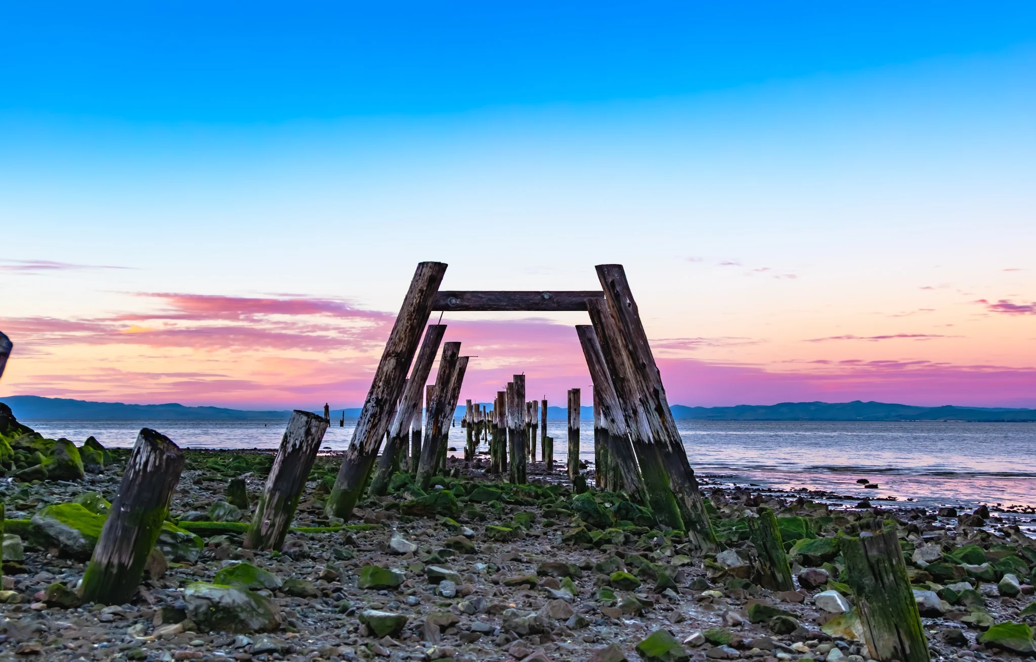 Weathered pier remains beneath a pastel sky